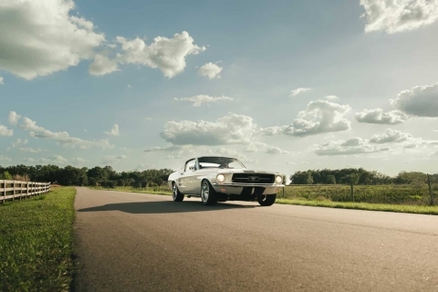 White restomod mustang driving on an open county road