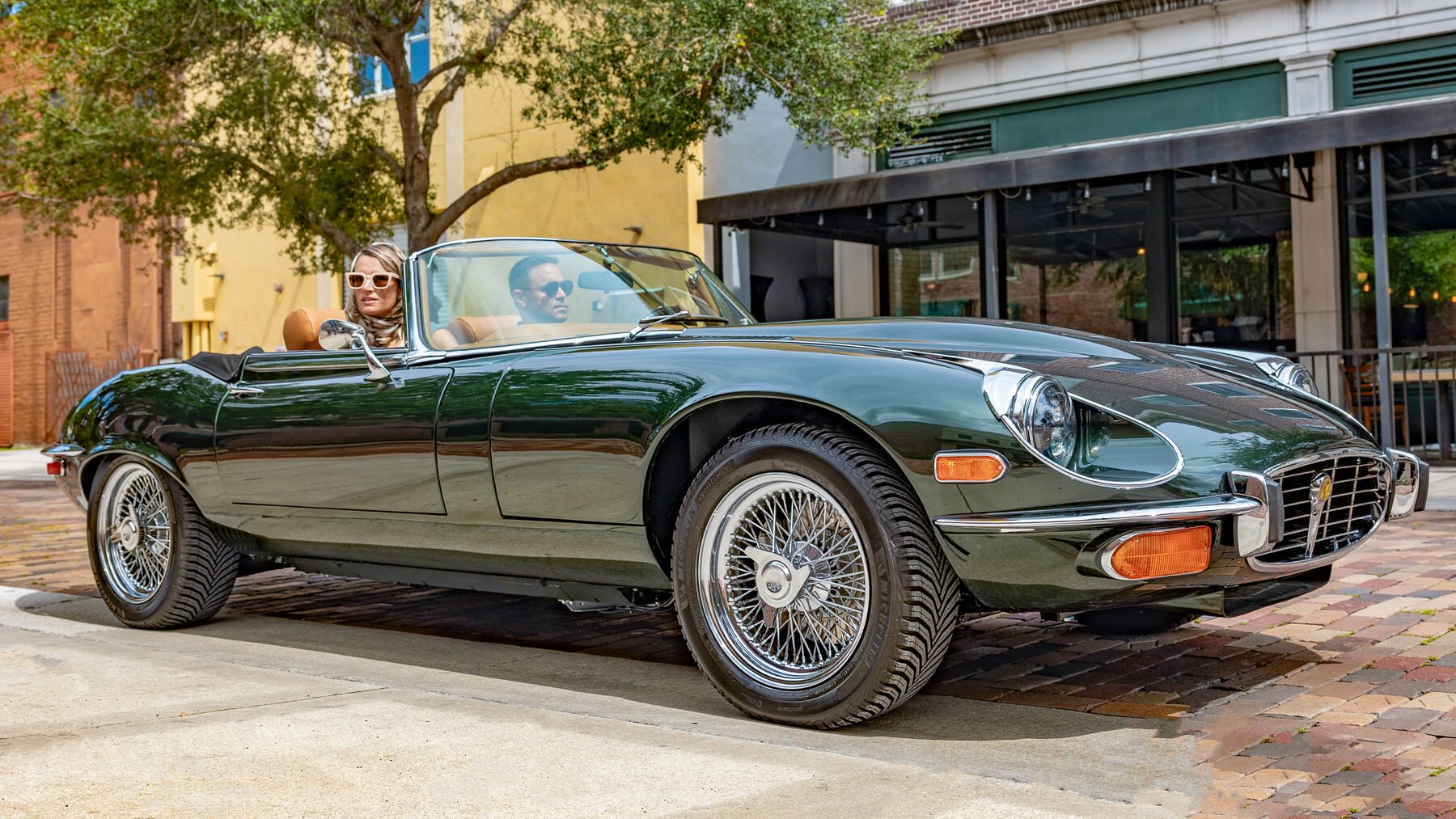 Couple driving a restored Jaguar E-Type in 2025